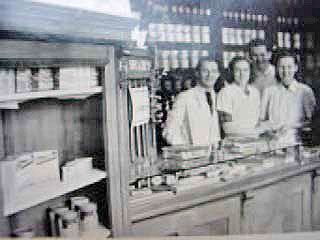 Alte Schwarz-Weiß-Fotografie zeigt Apotheken-Personal hinter HV-Tisch