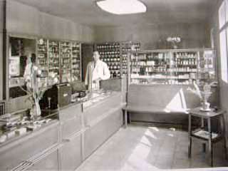 Alte Schwarz-Weiß-Fotografie, Apotheker hinter HV-Tisch